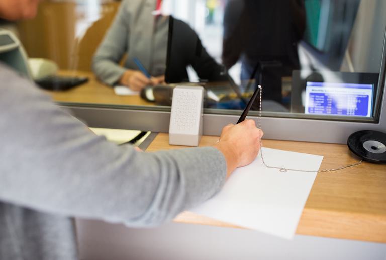 Community bank customer signing a document at a teller window